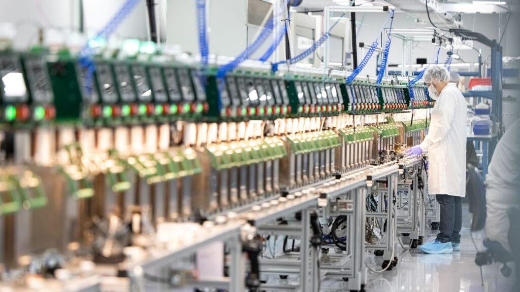 Cleanroom assembly line with person working on electronics.